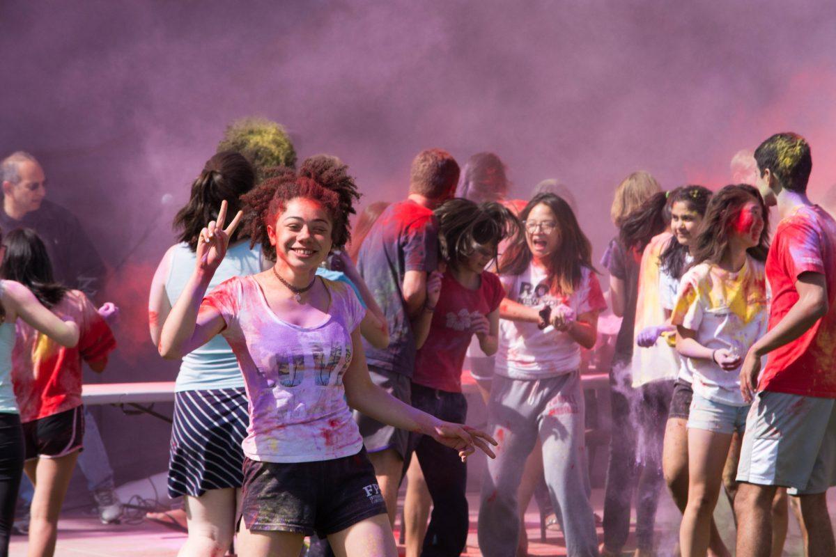 Nina G. poses as the students behind her engage in all-out paint warfare in celebration of Holi. Photo by Varun M.