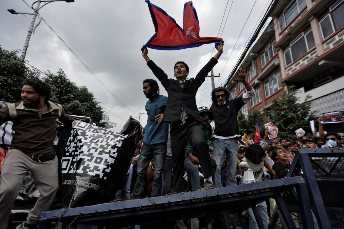The QR Code Banner: Young protesters climb the
barricade in Kathmandu.